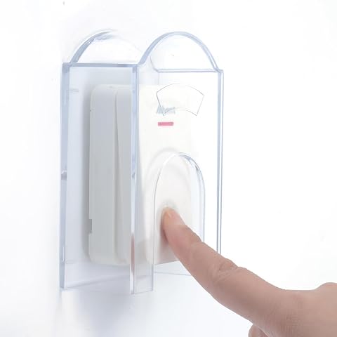 Capot de protection transparent fixé au mur devant un bouton de sonnette extérieur.